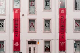 Casa Fernando Pessoa, Lisbon — the house museum with red banners spelling 'Museu Pessoa' down its façade.