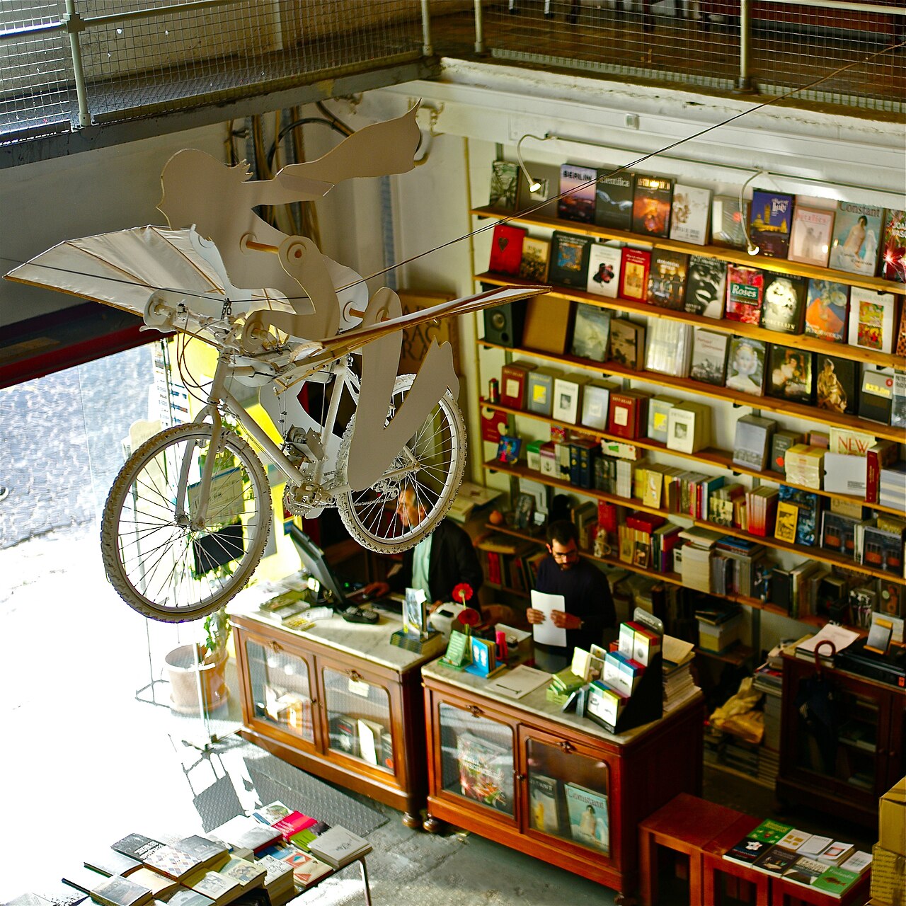 Ler Devagar bookshop, LX Factory, Lisbon — a two-storey bookshop with a flying bicycle sculpture suspended above the shelves.